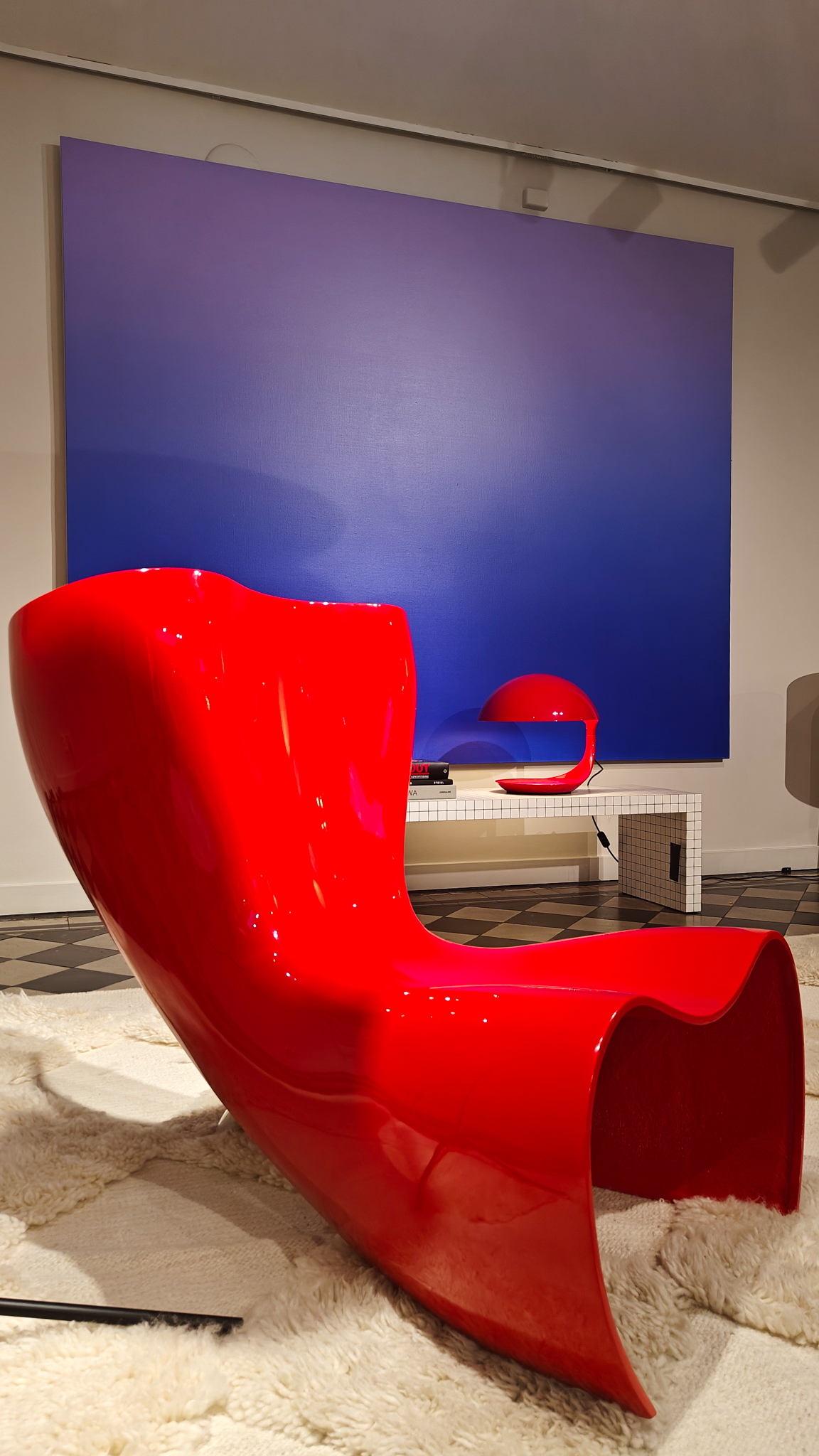 Cadira de disseny futurista de color vermell brillant amb llum vermella i fons blau a la Stockholm Design Week.